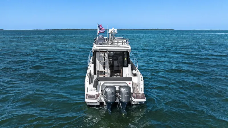 Trinity Yacht Photos Pics 2020 Jeanneau NC 1095 Fly boat on open water, rear view with dual engines.