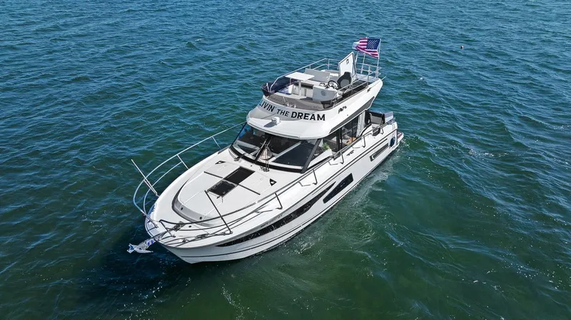 Trinity Yacht Photos Pics 2020 Jeanneau NC 1095 Fly yacht cruising on open water with American flag.