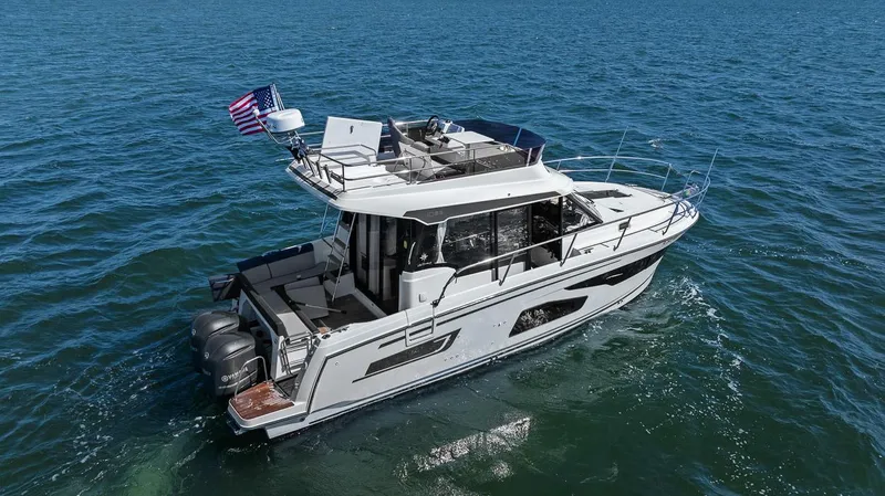 Trinity Yacht Photos Pics 2020 Jeanneau NC 1095 Fly boat cruising on open water with American flag.