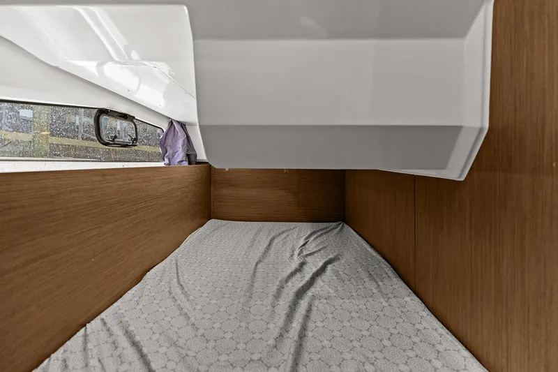 Trinity Yacht Photos Pics Interior cabin of 2020 Jeanneau NC 1095 Fly, featuring a cozy bed and wooden paneling.