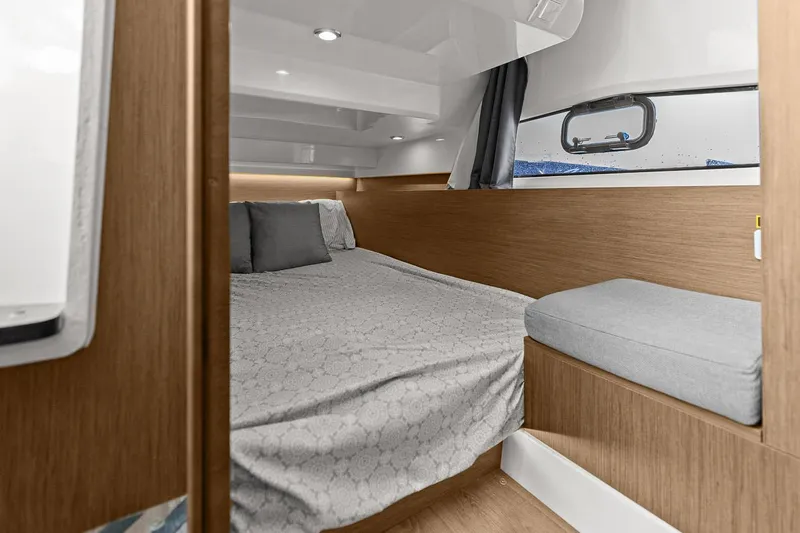 Trinity Yacht Photos Pics Cozy cabin interior of 2020 Jeanneau NC 1095 Fly with bed and seating area.