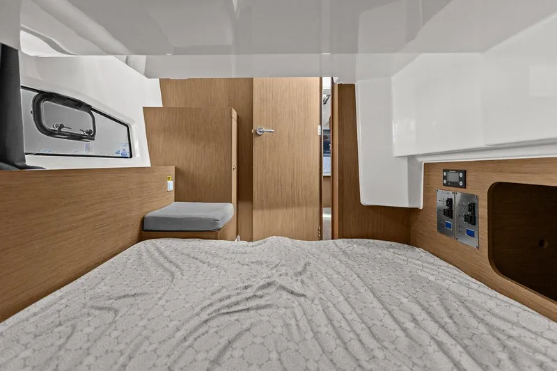 Trinity Yacht Photos Pics Interior cabin of 2020 Jeanneau NC 1095 Fly, featuring wood accents and a cozy bed.