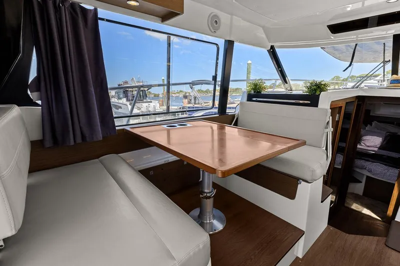 Trinity Yacht Photos Pics Interior of 2020 Jeanneau NC 1095 Fly yacht with dining area and scenic window view.