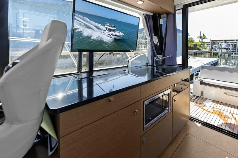 Trinity Yacht Photos Pics Modern interior of 2020 Jeanneau NC 1095 Fly yacht with sleek kitchen and scenic view.