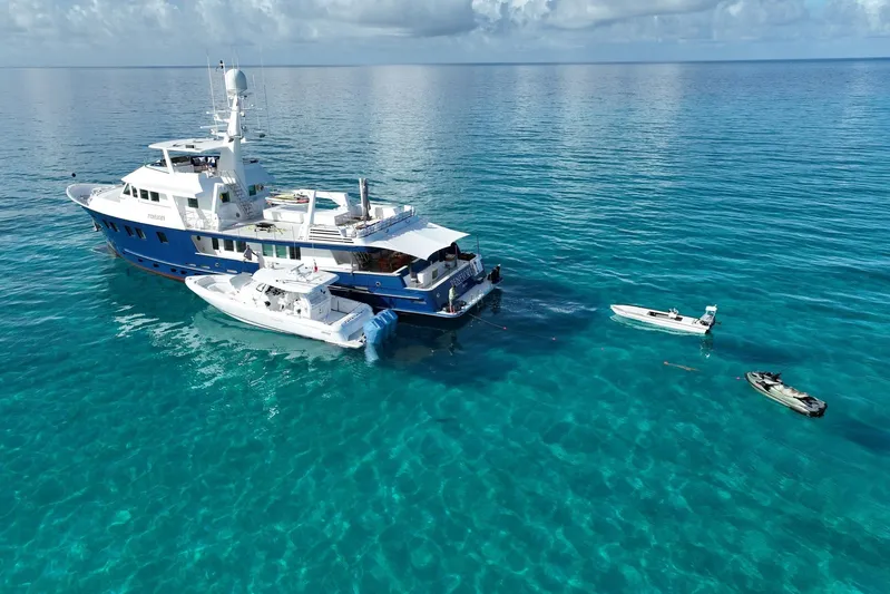 Penelope Yacht Photos Pics Aerial view of 1990 Delta Expedition yacht with boats in clear blue ocean.