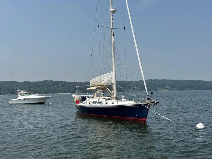 Elena Yacht Photos Pics Sailboat Hylas 46, 1998 model, anchored on calm water with scenic background.