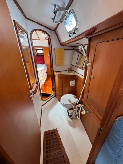 Elena Yacht Photos Pics Hylas 46 yacht bathroom with wooden interior, shower, and adjacent bedroom view.