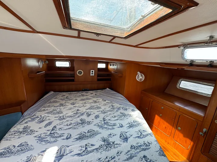 Elena Yacht Photos Pics Cozy cabin interior of 1998 Hylas 46 yacht with nautical-themed bedding and wooden furnishings.