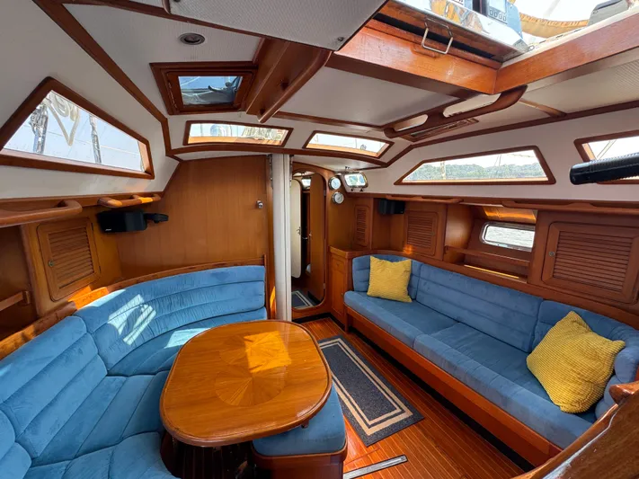 Elena Yacht Photos Pics Luxurious 1998 Hylas 46 yacht interior with blue seating, wooden table, and skylights.