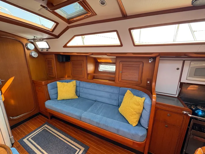 Elena Yacht Photos Pics Interior of 1998 Hylas 46 yacht with blue sofa, yellow cushions, and wooden cabinetry.