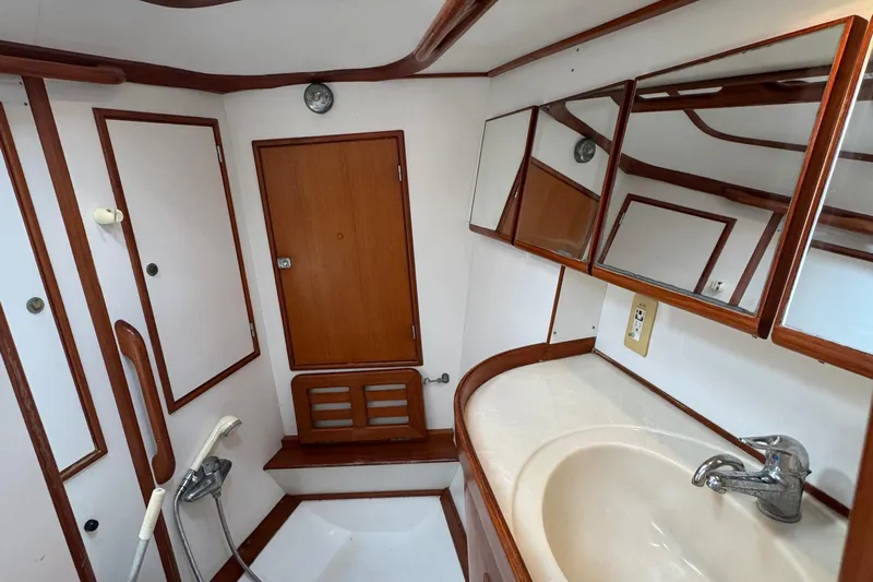 Elena Yacht Photos Pics Bathroom interior of a 1998 Hylas 46 yacht with wooden accents and mirrors.