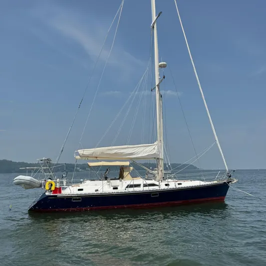 Elena Yacht Photos Pics Sailboat Hylas 46, 1998 model, anchored on calm water under a clear blue sky.