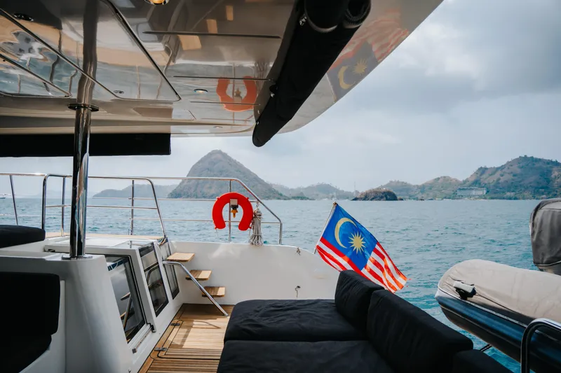  Yacht Photos Pics 2017 Lagoon 630 Motor Yacht with Malaysian flag, scenic ocean view, and distant islands.