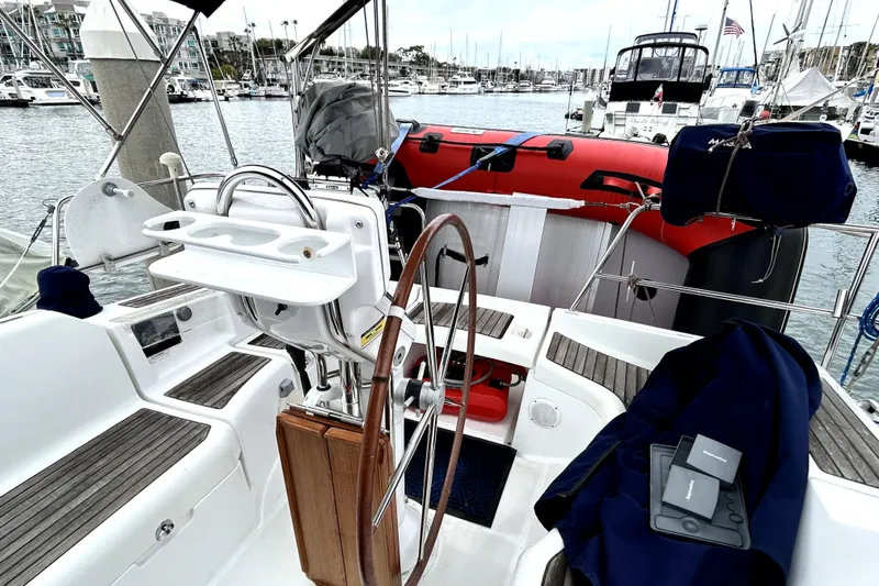 Notos Yacht Photos Pics Cockpit of 2005 Beneteau Oceanis 373 sailboat docked in marina, featuring steering wheel and seating.