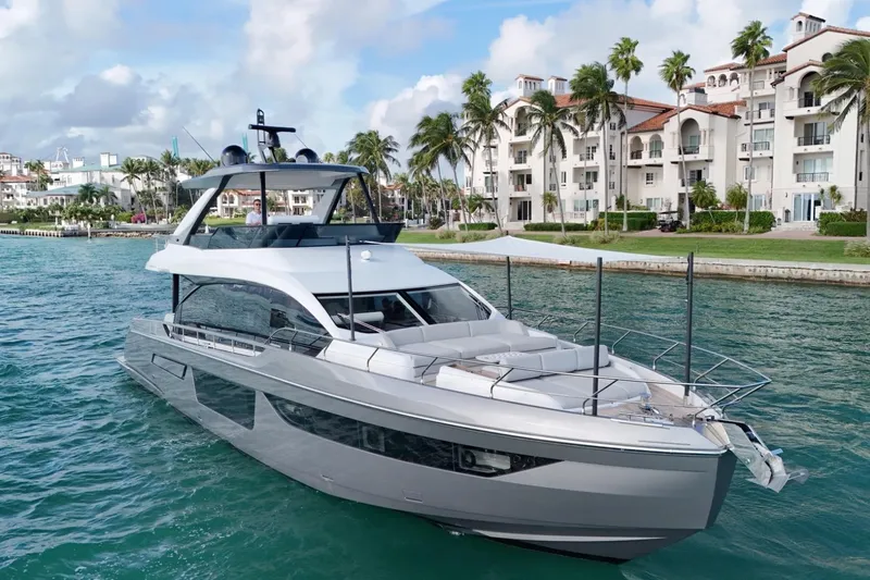  Yacht Photos Pics Luxurious 2023 Azimut Fly 68 yacht cruising near waterfront villas and palm trees.