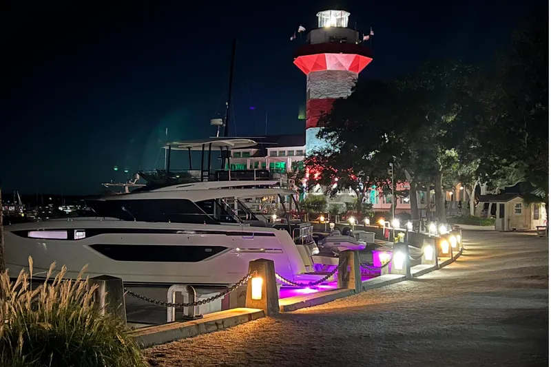 Yacht Photos Pics Luxurious 2023 Prestige M48 yacht docked at night near illuminated lighthouse.