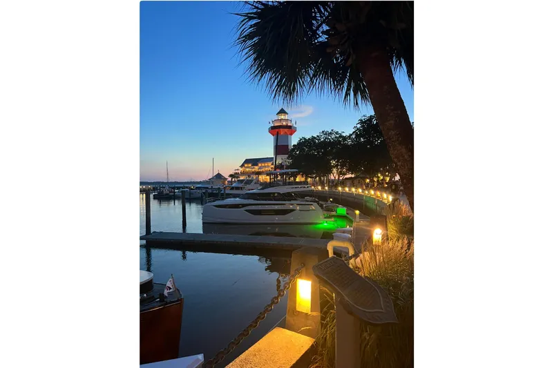  Yacht Photos Pics Sunset view of a marina with a lighthouse and 2023 Prestige M48 yacht.