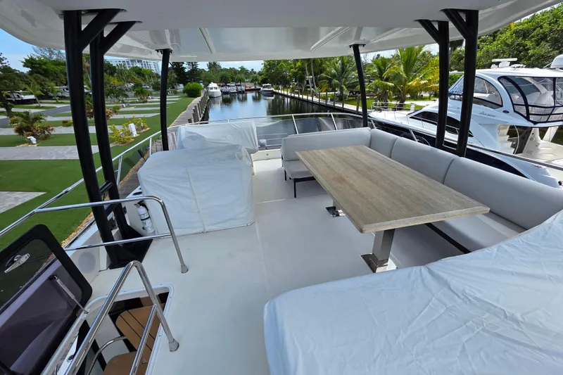  Yacht Photos Pics Luxury deck of 2023 Prestige M48 yacht with seating and table, docked by a canal.