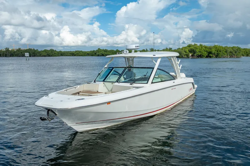 Trade In-- Bring All Offers & Trades Yacht Photos Pics 2024 Boston Whaler 320 Vantage boat cruising on a calm lake under a cloudy sky.