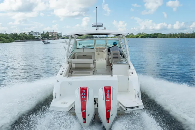 Trade In-- Bring All Offers & Trades Yacht Photos Pics 2024 Boston Whaler 320 Vantage cruising on a scenic waterway, rear view.