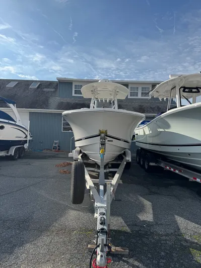 25 Regulator In Stock Yacht Photos Pics 2018 Regulator 25 boat on trailer, parked between two other boats, under a clear sky.