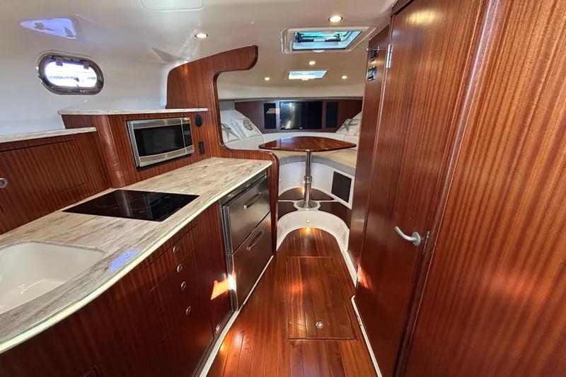  Yacht Photos Pics 2018 Pursuit OS 385 Offshore interior with wood finish, kitchenette, and dining area.