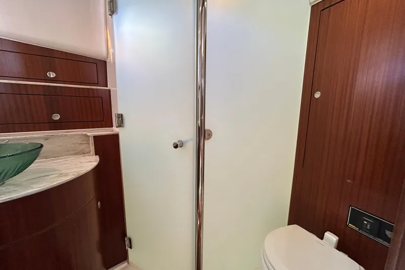  Yacht Photos Pics 2018 Pursuit OS 385 Offshore yacht bathroom with frosted glass door and wooden cabinetry.