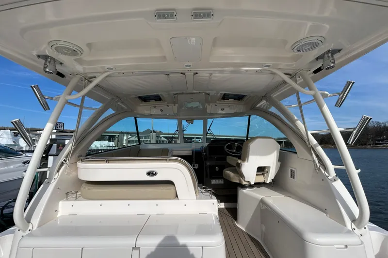  Yacht Photos Pics 2018 Pursuit OS 385 Offshore boat interior with seating and helm, docked by the water.