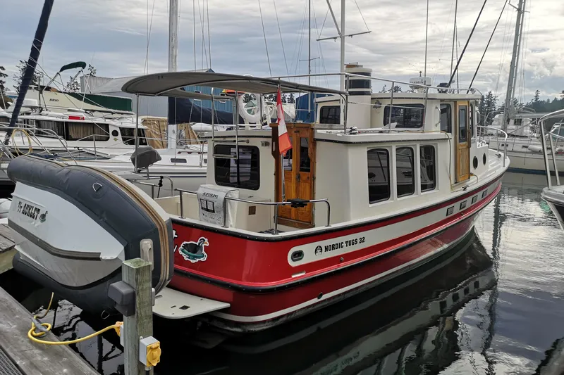  Yacht Photos Pics 1990 Nordic Tug 32 docked in marina, featuring red and white exterior.