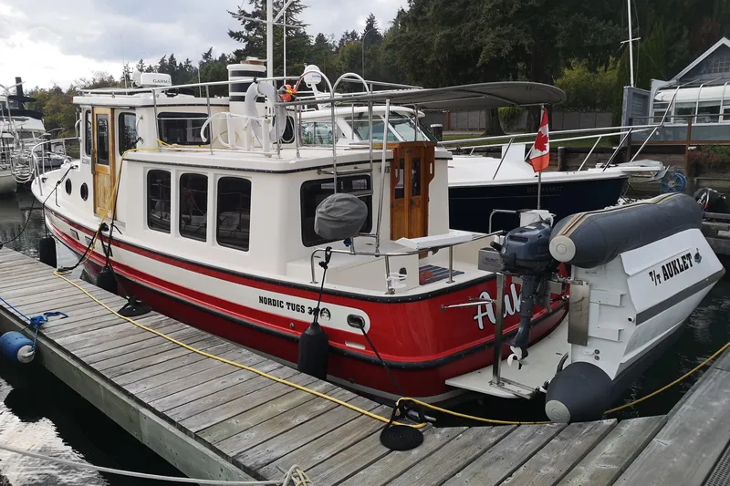  Yacht Photos Pics 1990 Nordic Tug 32 docked, featuring red and white design with Canadian flag.