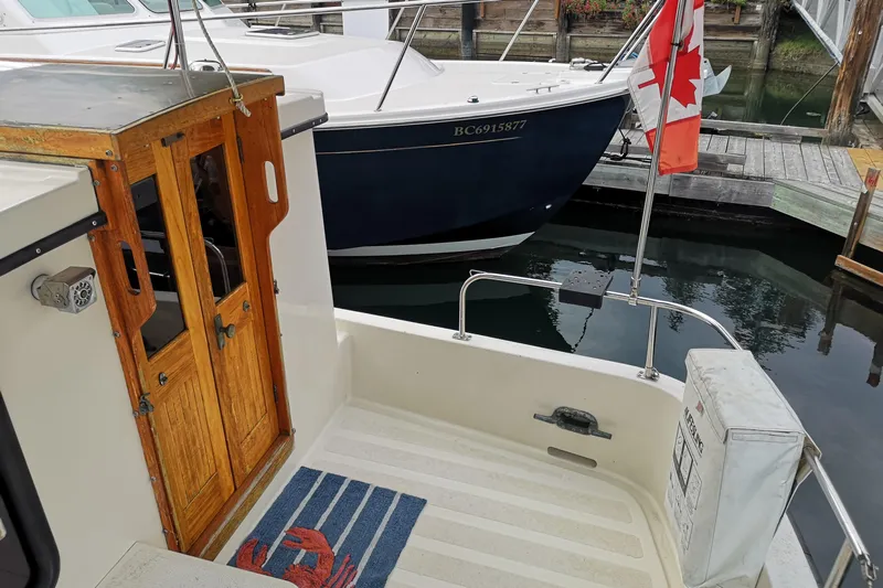  Yacht Photos Pics 1990 Nordic Tug 32 docked, featuring wooden doors and Canadian flag.