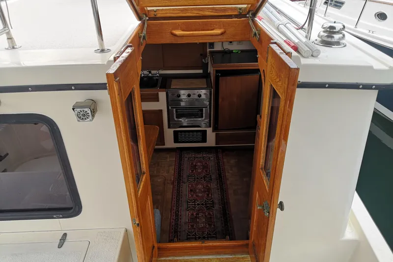  Yacht Photos Pics Interior view of a 1990 Nordic Tug 32, featuring wooden doors and a compact kitchen.
