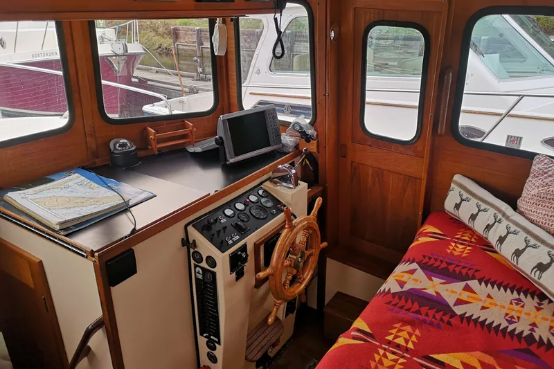  Yacht Photos Pics Cozy 1990 Nordic Tug 32 interior with helm, navigation tools, and vibrant seating.