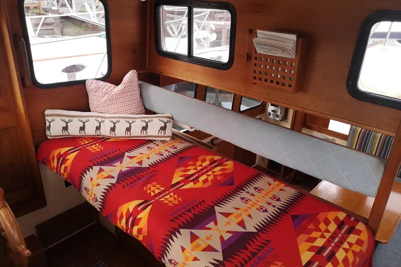  Yacht Photos Pics Cozy interior of 1990 Nordic Tug 32 with vibrant geometric-patterned bedding and decorative pillows.