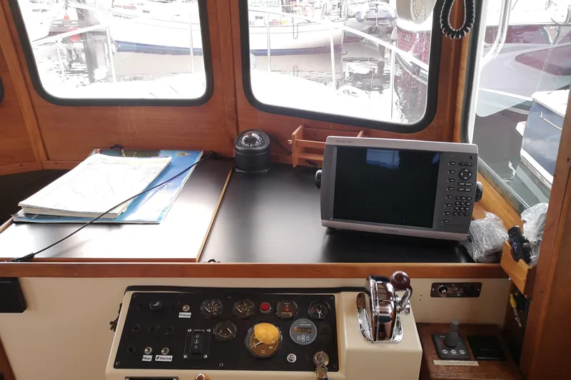  Yacht Photos Pics Nordic Tug 32 (1990) helm with navigation equipment and charts in a marina setting.