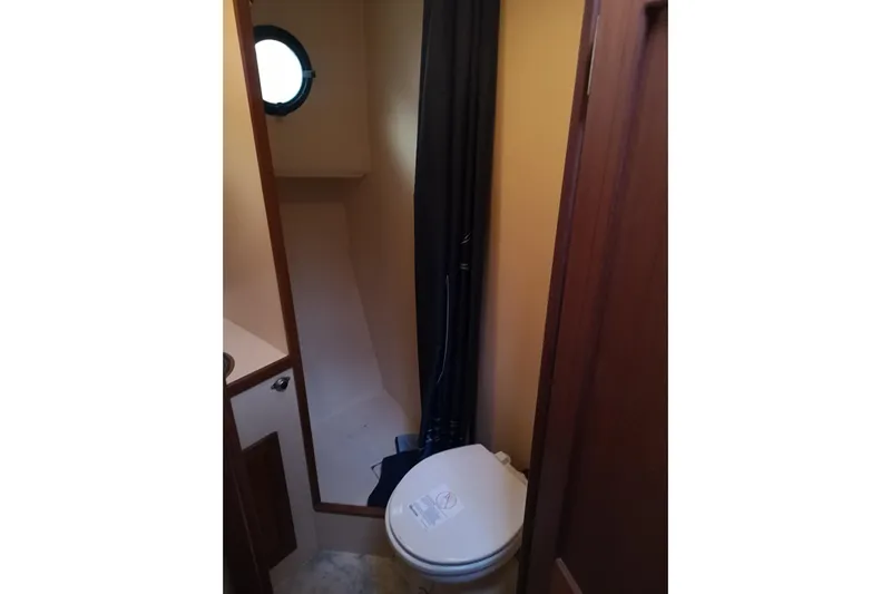  Yacht Photos Pics 1990 Nordic Tug 32 bathroom with toilet and shower, featuring a porthole window.