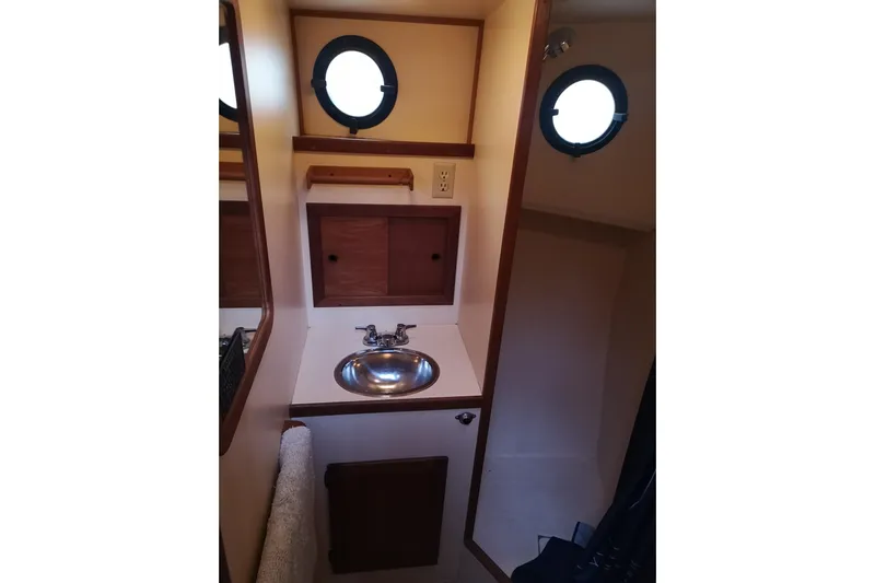  Yacht Photos Pics 1990 Nordic Tug 32 bathroom with sink, portholes, and wooden cabinetry.