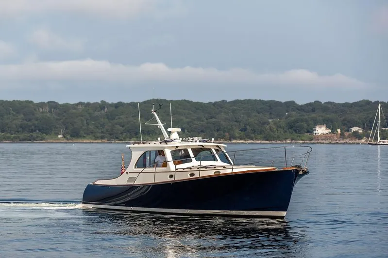 Summer Yacht Photos Pics 2002 Hinckley Talaria 44 yacht cruising on calm waters near a forested shoreline.