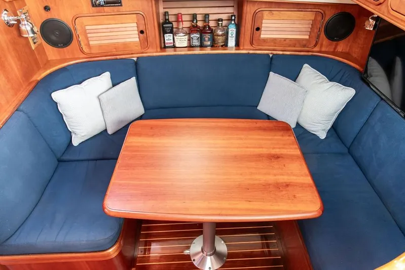 Summer Yacht Photos Pics Cozy interior of 2002 Hinckley Talaria 44 yacht with blue seating and wooden table.