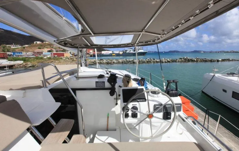 Anila Yacht Photos Pics Helia 44 Evolution catamaran cockpit with steering wheel, ocean view, and marina backdrop.