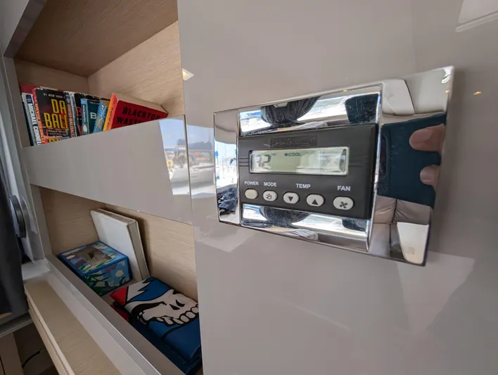 Anila Yacht Photos Pics Control panel on 2018 Fountaine Pajot Helia 44 Evolution yacht, with books and decor nearby.