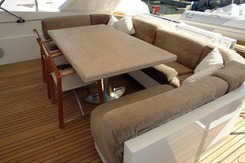  Yacht Photos Pics Outdoor seating area on a 2006 Sanlorenzo SL88 yacht with a wooden table and cushioned benches.