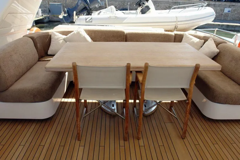  Yacht Photos Pics Outdoor dining area on a 2006 Sanlorenzo SL88 yacht with wooden table and cushioned seating.
