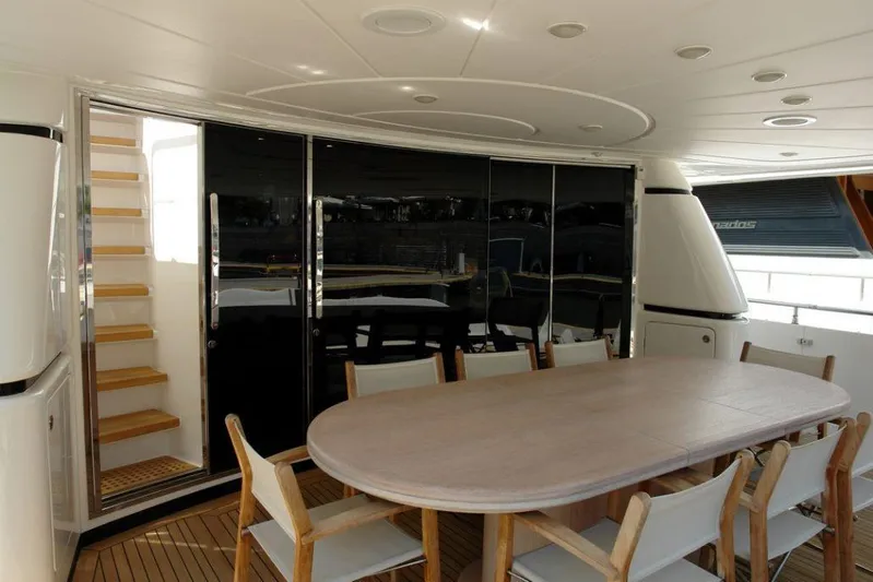  Yacht Photos Pics Outdoor dining area on 2006 Sanlorenzo SL88 yacht with wooden table and chairs.
