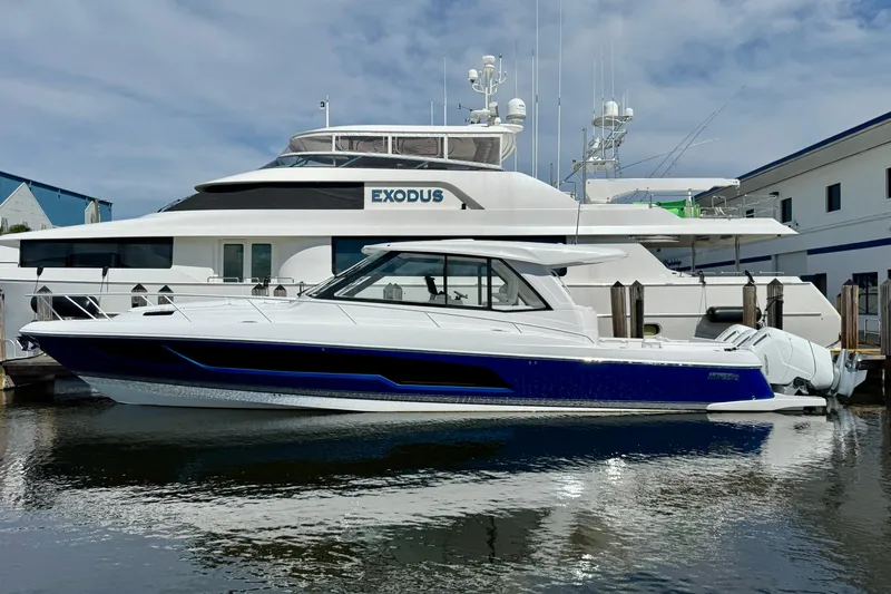  Yacht Photos Pics 2026 Intrepid 50 Evolution yacht docked beside a larger vessel, reflecting on calm water.