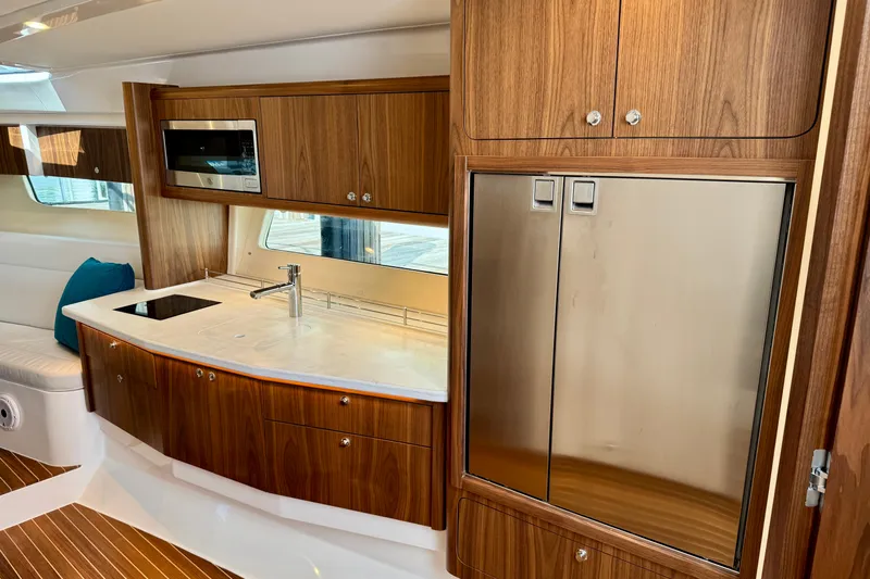  Yacht Photos Pics Luxurious kitchen interior of 2026 Intrepid 50 Evolution yacht with wood cabinetry and stainless appliances.