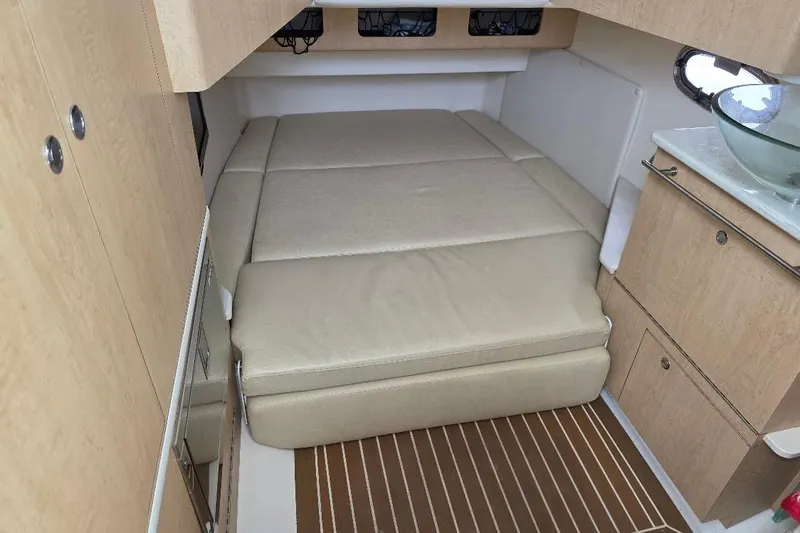  Yacht Photos Pics 2016 Boston Whaler 370 Outrage cabin interior with beige bedding and wooden cabinetry.