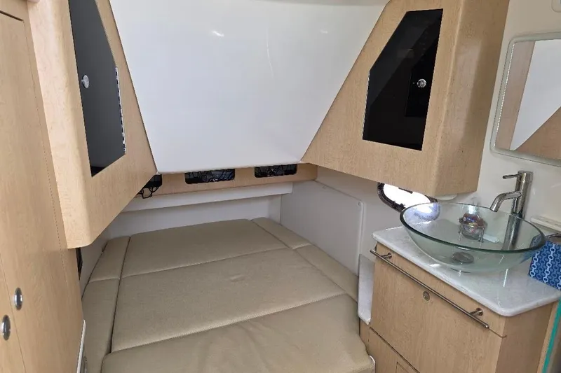  Yacht Photos Pics 2016 Boston Whaler 370 Outrage cabin interior with bed, sink, and wooden cabinetry.