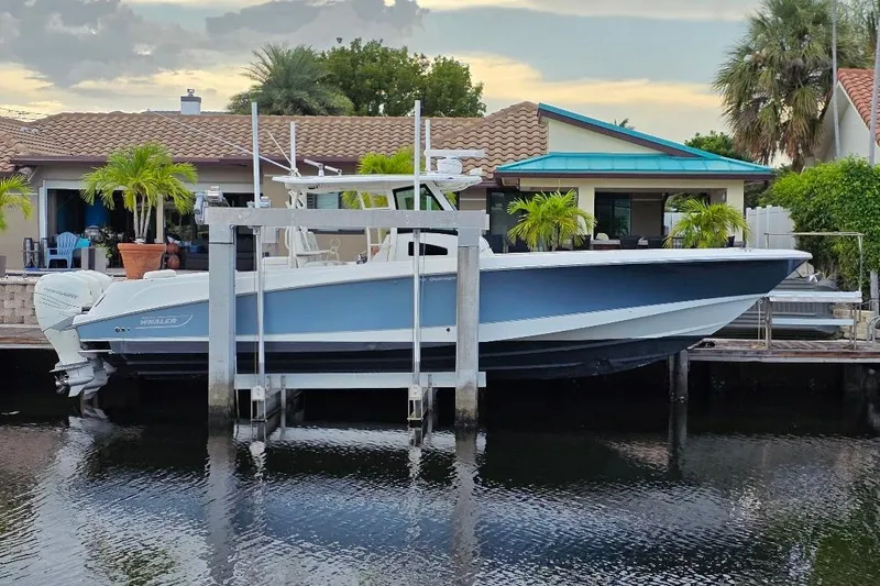  Yacht Photos Pics 2016 Boston Whaler 370 Outrage boat docked by a waterfront home with palm trees.