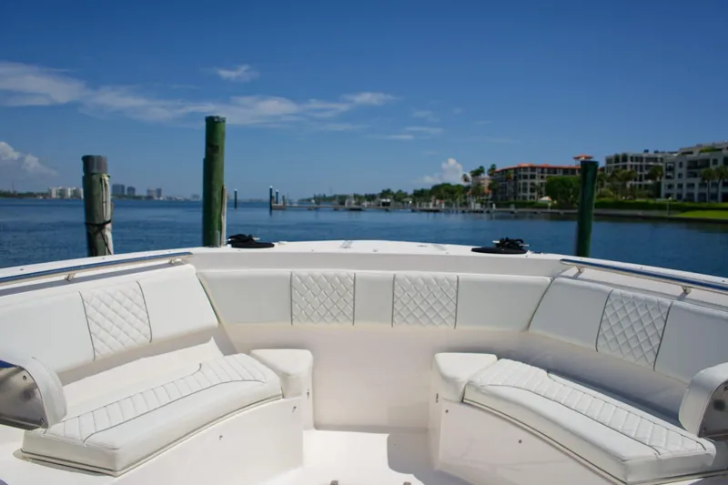 W7 Yacht Photos Pics 2022 Pursuit S 428 Sport boat interior with white seating, docked by waterfront homes.